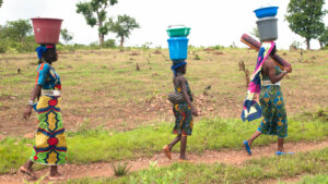 カメルーン、ポリで頭に水の容器をのせて歩くムボロロ族の女性たち